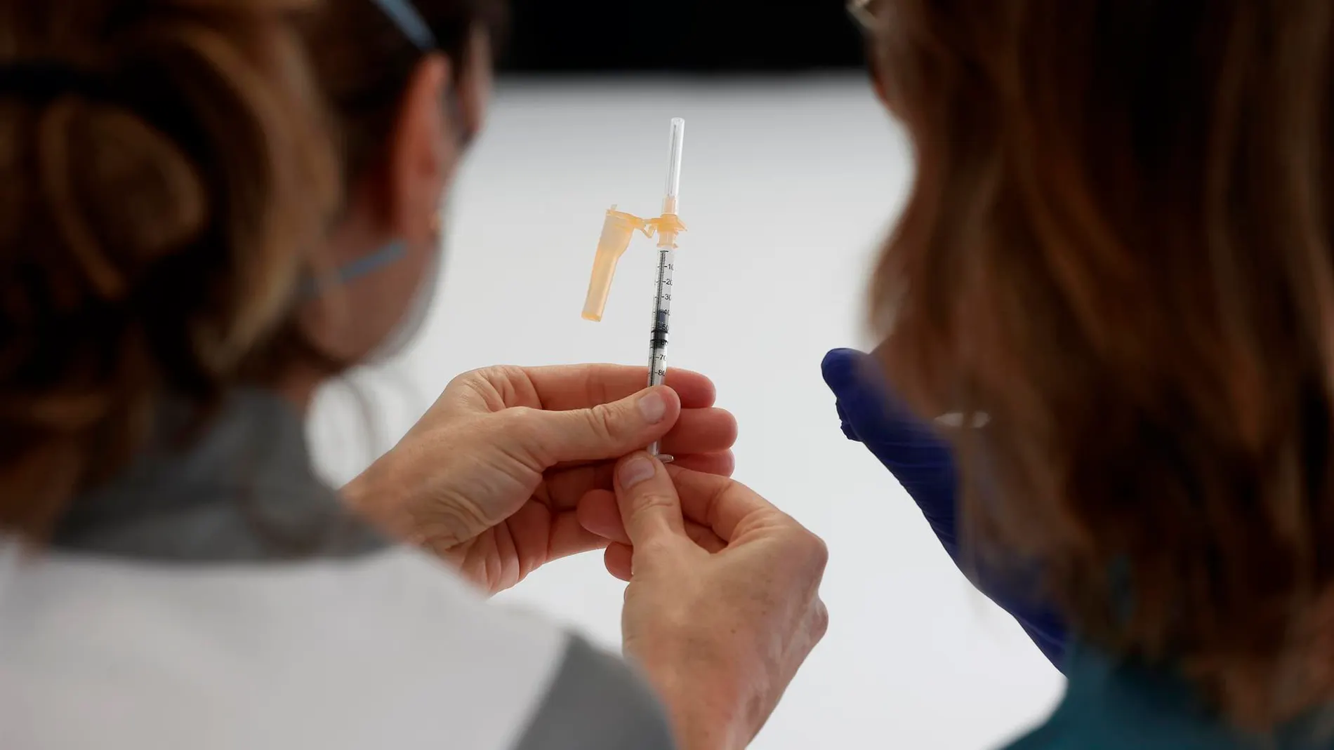 Dos enfermeras observan una dosis de la vacuna, en foto de archivo