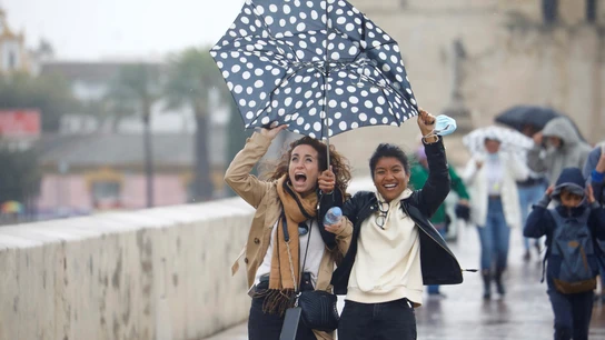 Unas turistas intentan protegerse del viento y de la lluvia con un paraguas mientras caminan por el puente romano de Córdoba Unas turistas intentan protegerse del viento y de la lluvia con un paraguas mientras caminan por el puente romano de Córdoba