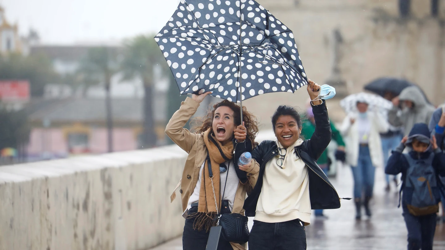 Unas turistas intentan protegerse del viento y de la lluvia con un paraguas mientras caminan por el puente romano de Córdoba Unas turistas intentan protegerse del viento y de la lluvia con un paraguas mientras caminan por el puente romano de Córdoba