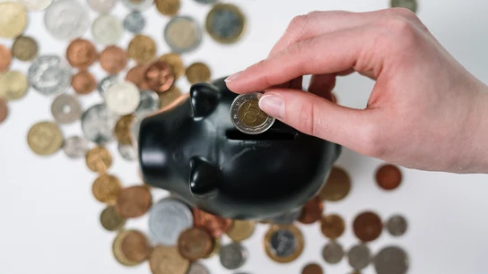 Imagen de archivo de una persona introduciendo dinero en una hucha Imagen de archivo de una persona introduciendo dinero en una hucha