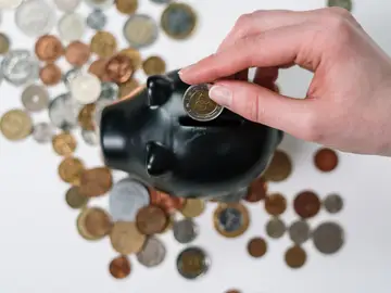 Imagen de archivo de una persona introduciendo dinero en una hucha