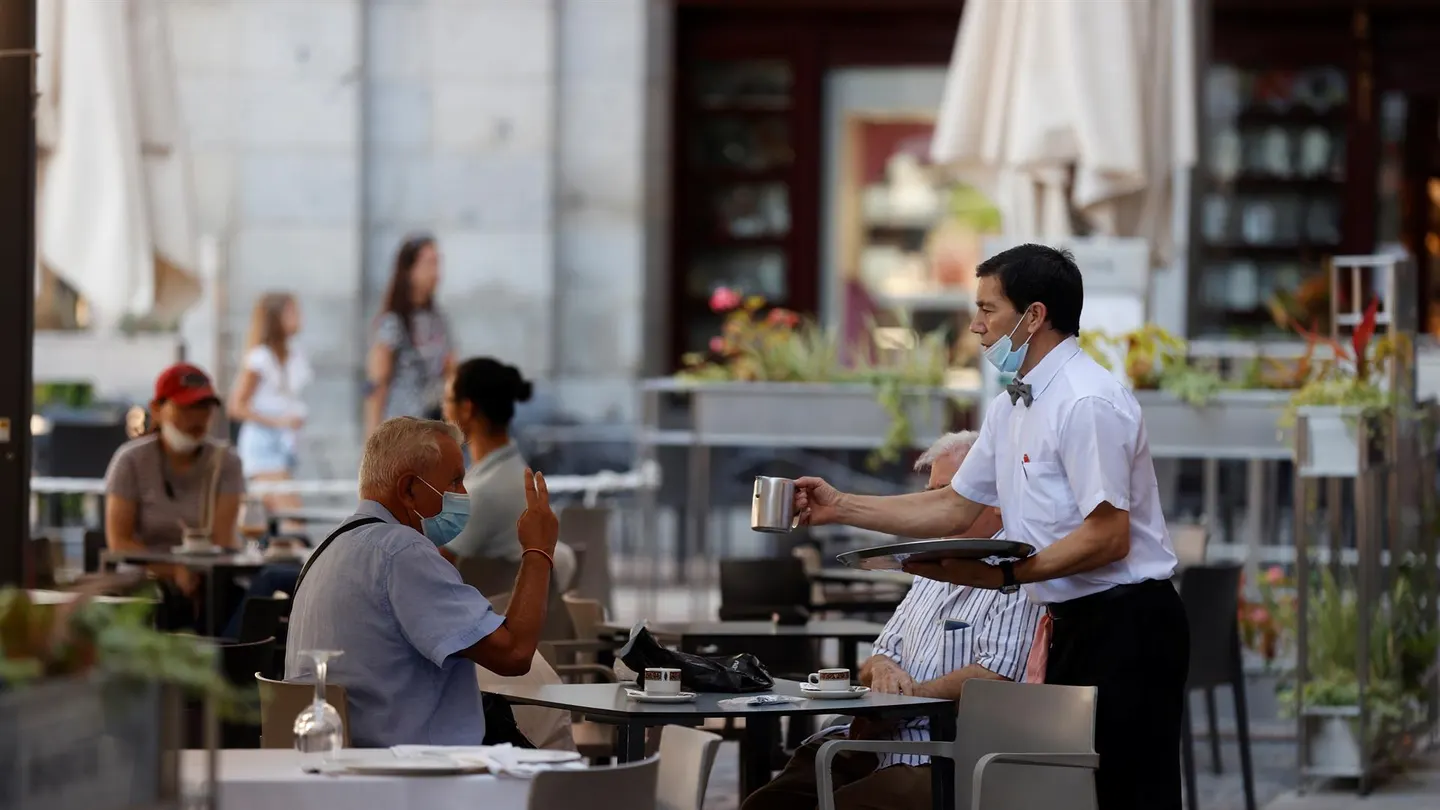 Un camarero atendiendo en una terraza Un camarero atendiendo en una terraza