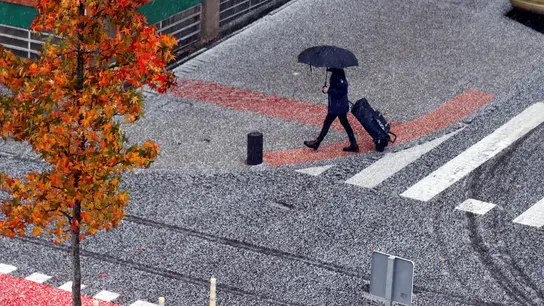 Un viandante camina entre el granizo y la lluvia en una imagen de archivo Un viandante camina entre el granizo y la lluvia en una imagen de archivo