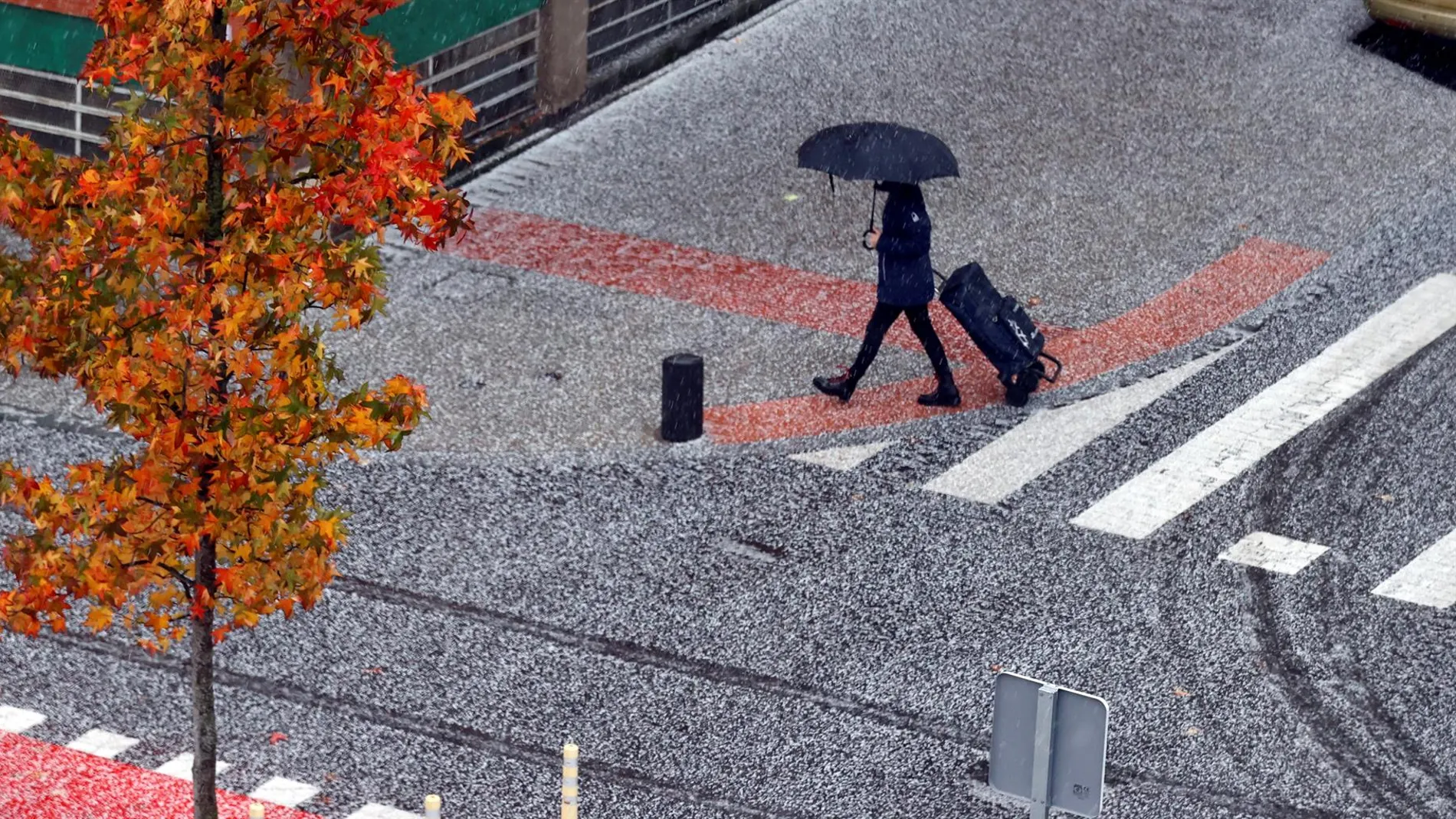 Un viandante camina entre el granizo y la lluvia en una imagen de archivo