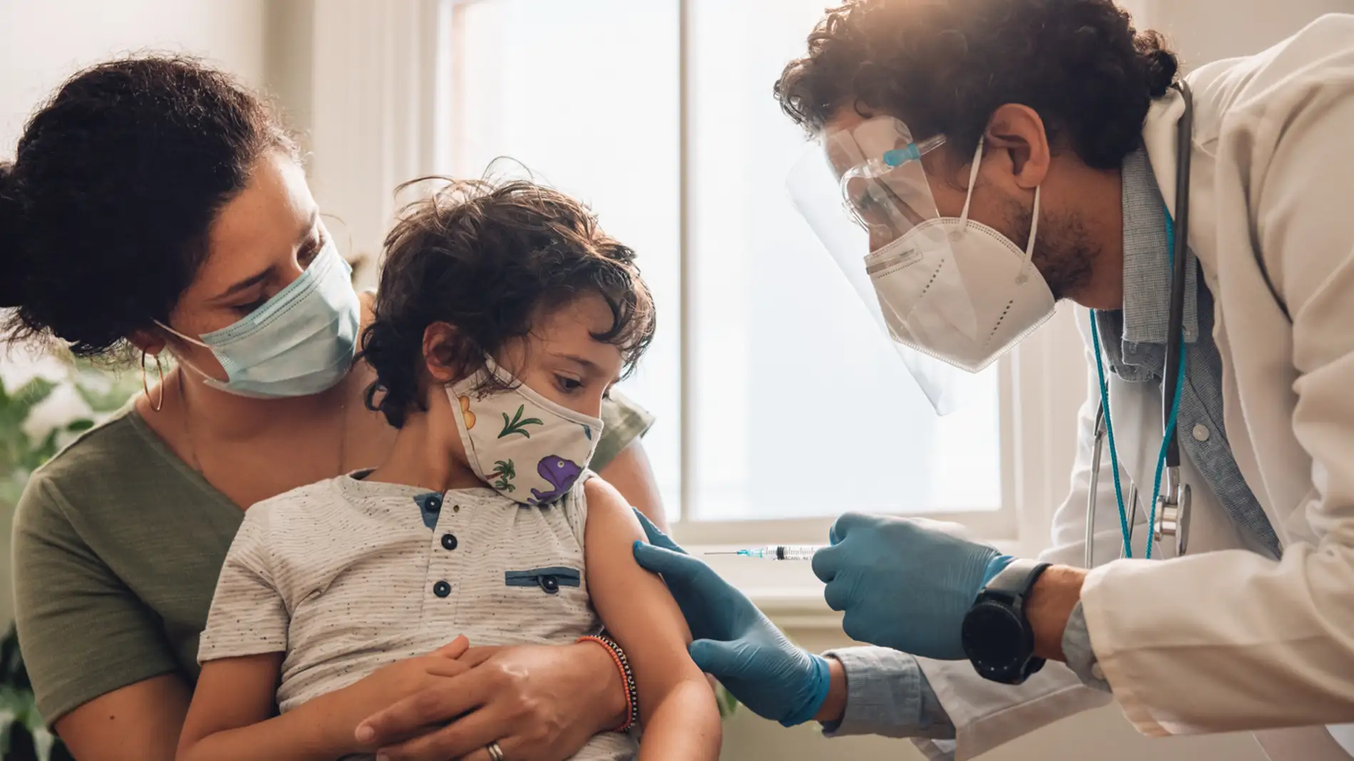 Niño con su madre y un sanitario que va a vacunarle