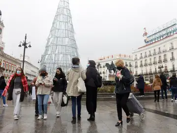  Varias personas caminan con mascarillas por la Puerta del Sol este viernes cuando el país ha llegado a la Navidad con cifras récord de contagios.