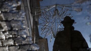 El reflejo en un charco de agua de una estrella de iluminación navideña colocada en la calle cuna en Sevilla.
