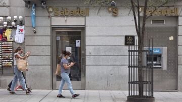 Varias personas pasan por una sucursal de Banco Sabadell en Madrid (España)