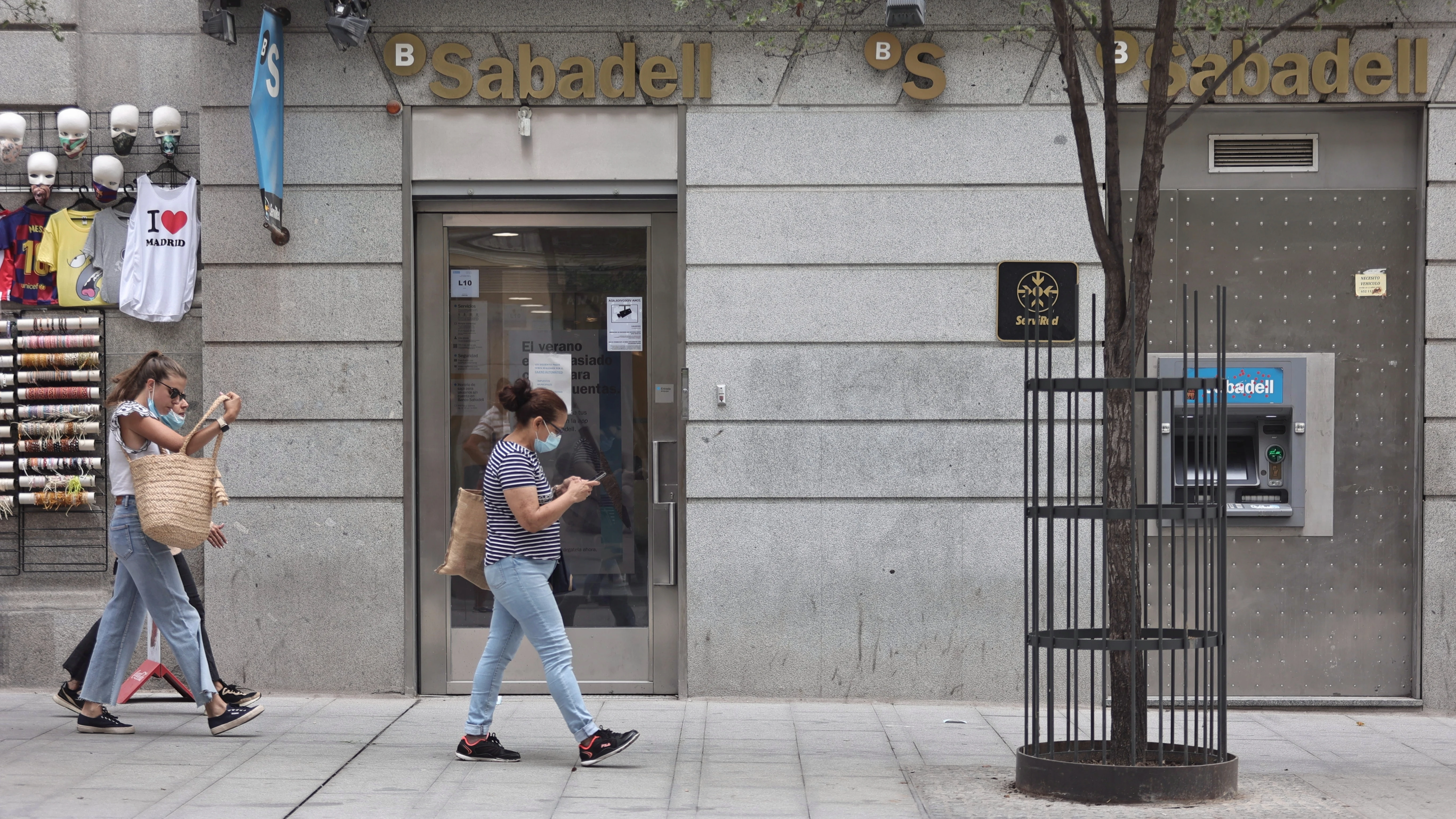 Varias personas pasan por una sucursal de Banco Sabadell en Madrid (España)