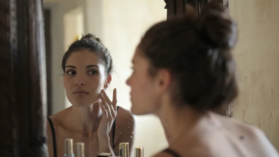 ¿Cómo afectan los excesos navideños a la salud de la piel? Chica mirándose al espejo