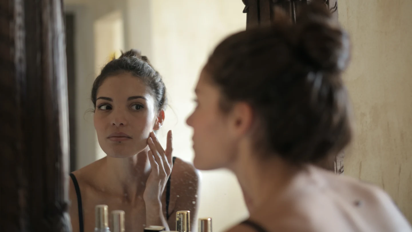 ¿Cómo afectan los excesos navideños a la salud de la piel? Chica mirándose al espejo