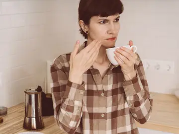 Mujer huele el café con una expresión desconcertada Mujer huele el café con una expresión desconcertada