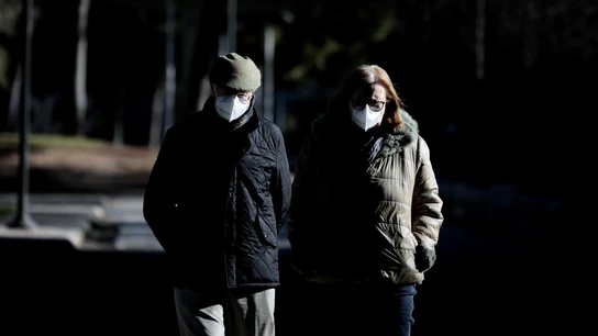 Dos personas pasean abrigadas y con la mascarilla puesta Dos personas pasean abrigadas y con la mascarilla puesta