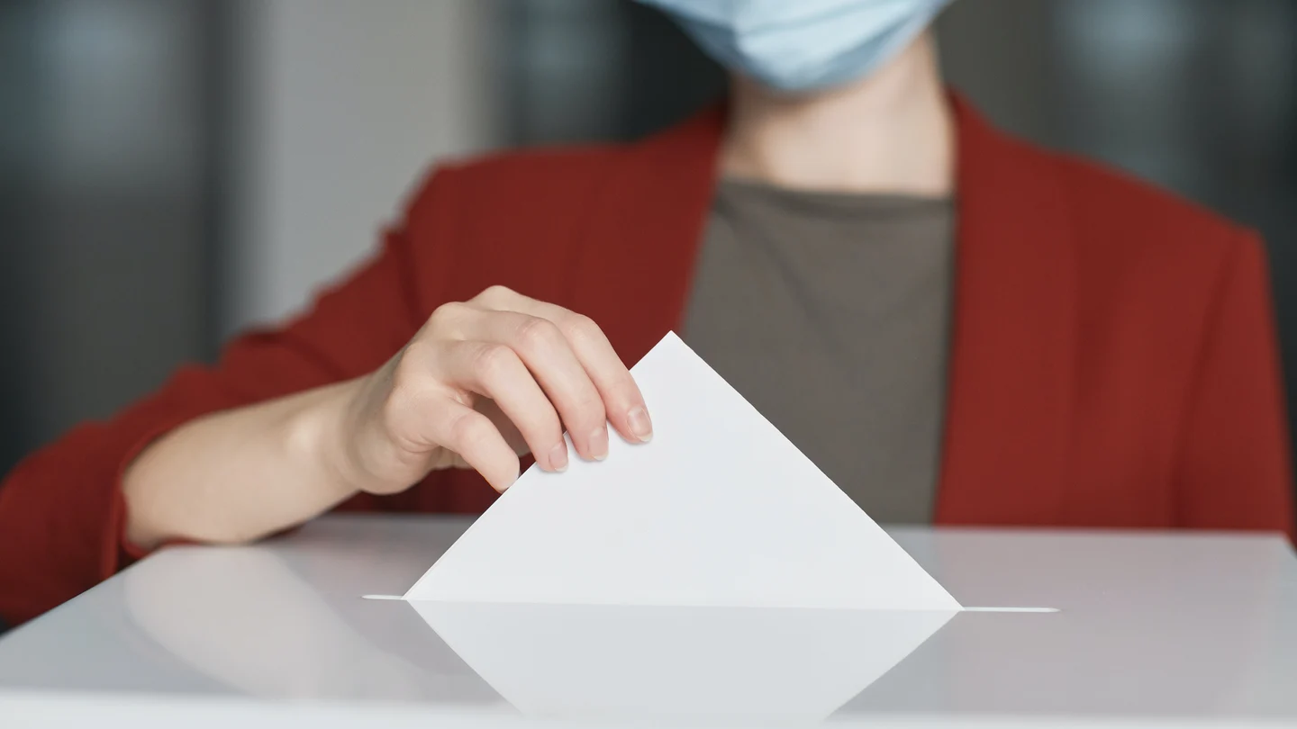Una persona depositando el voto en una urna electoral. Una persona depositando el voto en una urna electoral.