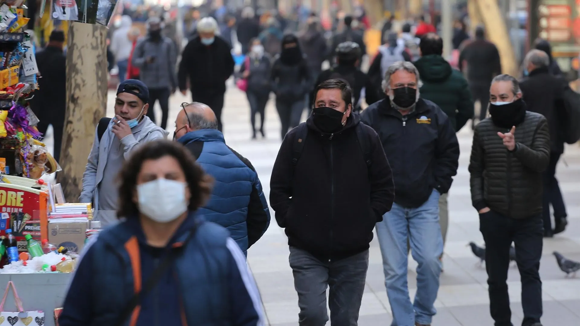 Varias personas pasean por la calle con mascarilla.