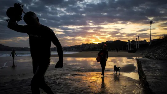 Dos hombres salen del agua al amanecer en la playa de Ondarreta de San Sebastián Dos hombres salen del agua al amanecer en la playa de Ondarreta de San Sebastián