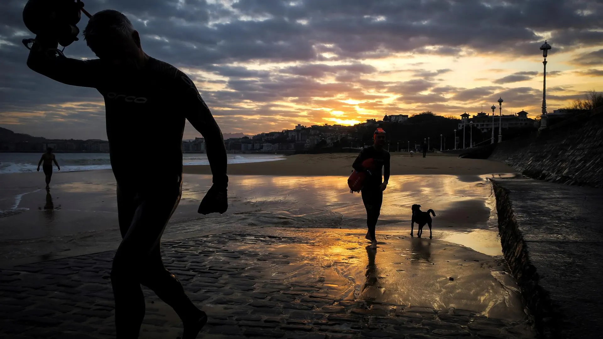 Dos hombres salen del agua al amanecer en la playa de Ondarreta de San Sebastián