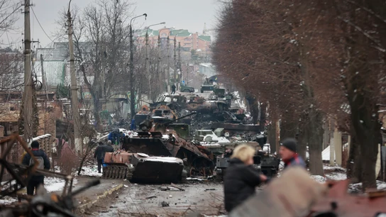 La gente mira los restos destripados de vehículos militares rusos en una carretera en la ciudad de Bucha, cerca de la capital, Kiev. La gente mira los restos destripados de vehículos militares rusos en una carretera en la ciudad de Bucha, cerca de la capital, Kiev.