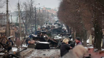 La gente mira los restos destripados de vehículos militares rusos en una carretera en la ciudad de Bucha, cerca de la capital, Kiev.