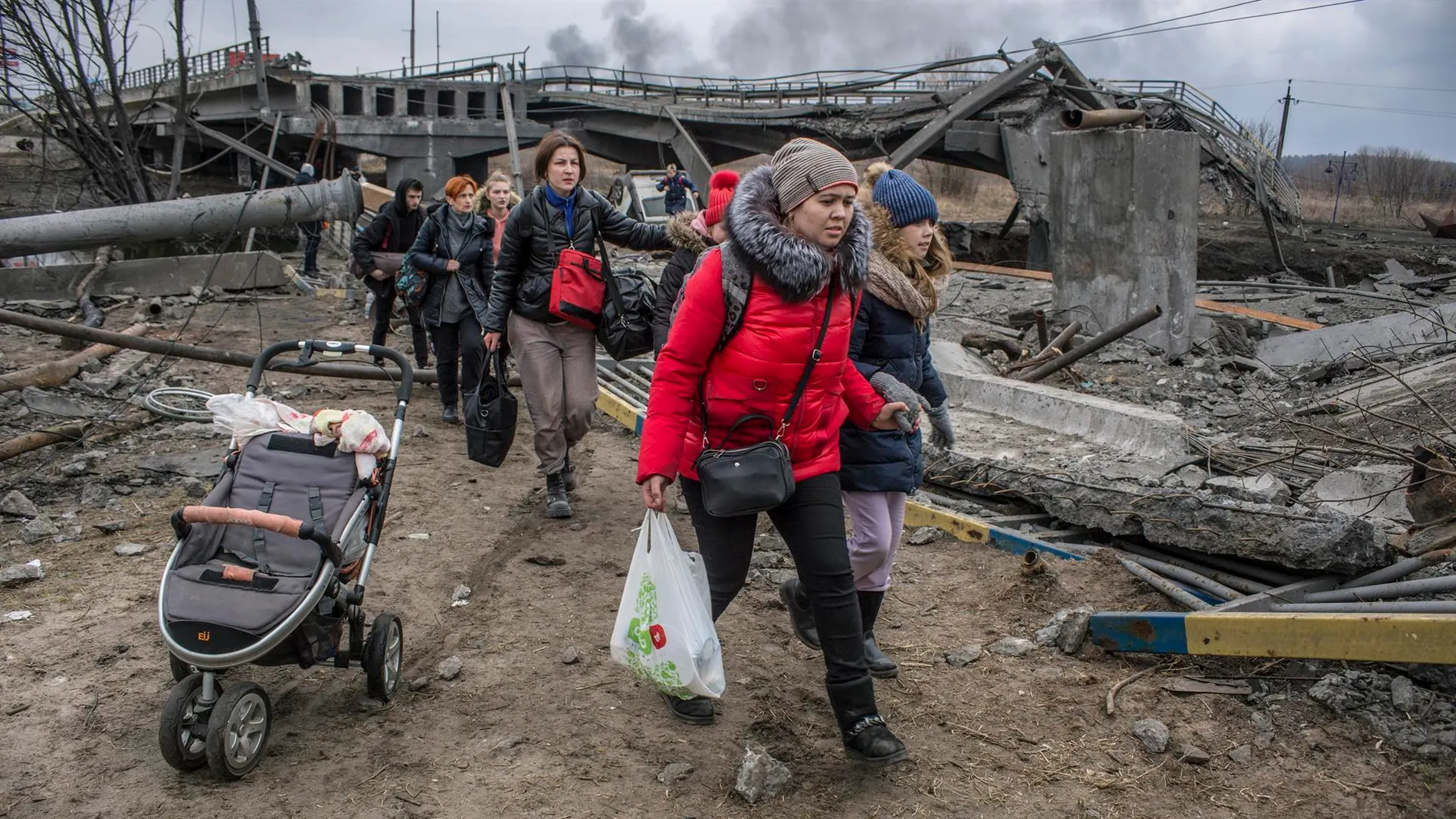 Los civiles cruzan entre los escombros de un puente dañado en la ciudad de Irpín cerca de Kiev