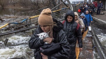 Ciudadanos ucranianos huyen de Irpín andando sobre un puente destruido
