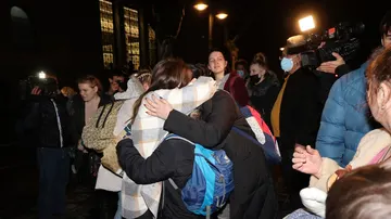 Dos personas se abrazan a su llegada a Valencia tras haber finalizado un viaje en autobús.