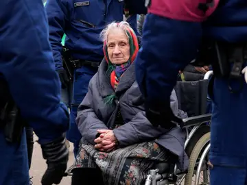 Una anciana que huyó de Ucrania está en una silla de ruedas esperando ayuda después de llegar a la estación de tren de Zakhon, Hungría.