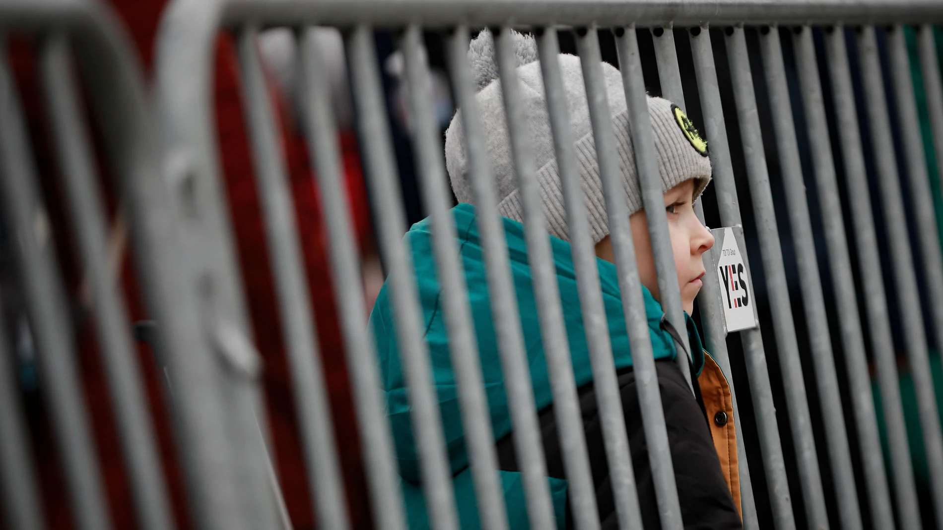 Un niño pequeño, que viaja con otras personas que huyen de Ucrania, mira a través de una barrera en el cruce fronterizo en Medyka, Polonia.