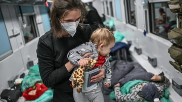 Una madre sostiene a su bebé dentro de un vagón de tren transformado para transporte médico