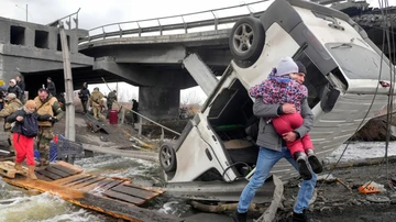 Personas cruzan un camino improvisado bajo un puente destruido en Irpin (Ucrania)