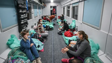 Madres sentadas junto a sus hijos en un vagón de tren transformado para el transporte médico