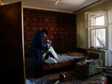 Vladimir Galinkov empaca sus pertenencias para evacuar su apartamento dañado después de que su edificio residencial fuera alcanzado por un misil interceptado en Kiev, Ucrania