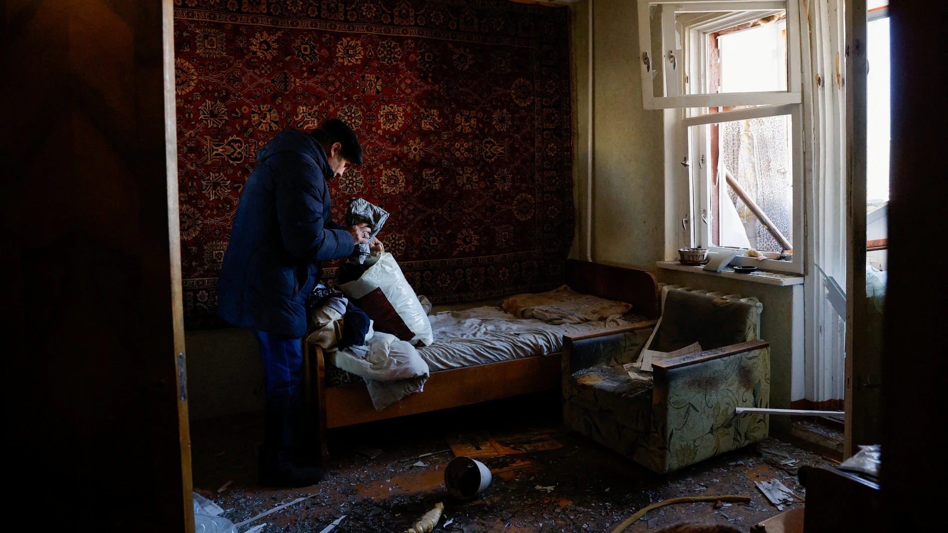 Vladimir Galinkov empaca sus pertenencias para evacuar su apartamento dañado después de que su edificio residencial fuera alcanzado por un misil interceptado en Kiev, Ucrania