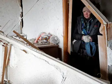 Una mujer se refugia bajo una casa en ruinas en Mariúpol