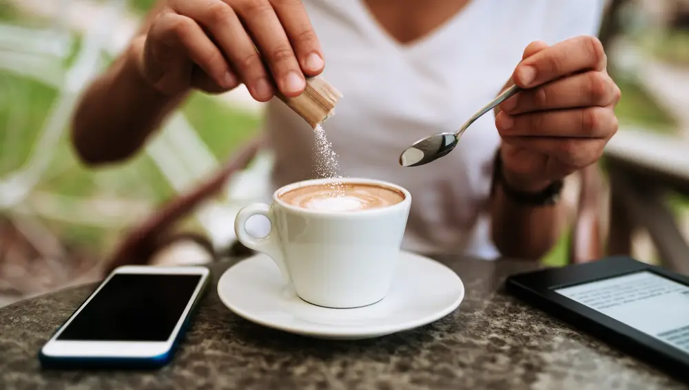 Mujer añadiendo azúcar a su café