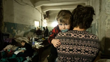 Una mujer sostiene a un niño en un refugio antiaéreo improvisado en Mariúpol