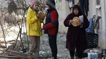 Un grupo de ciudadanos come pan en las calles destruidas de Mariúpol.