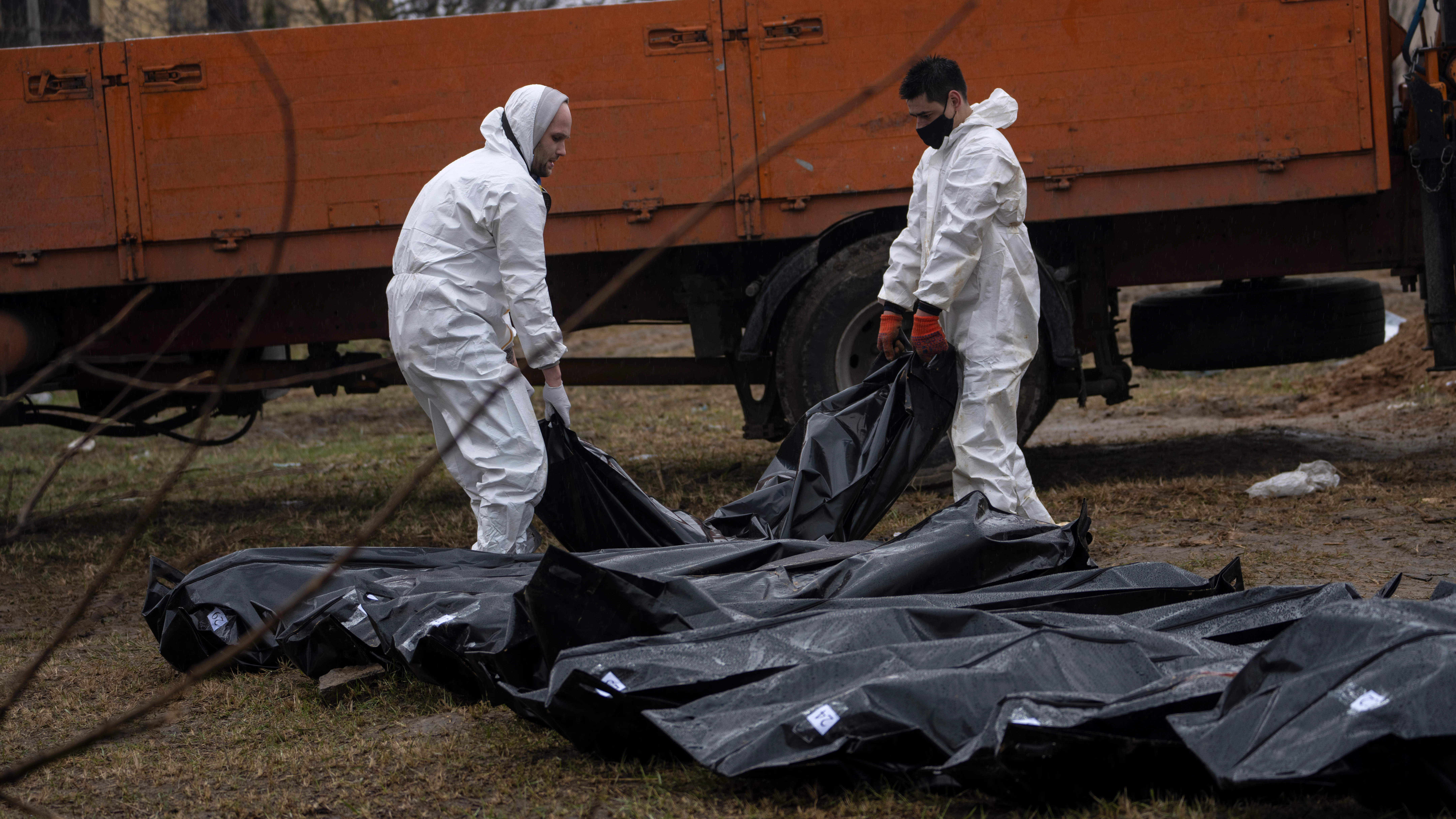 Cemetery workers carry a corpse of a man from a mass grave to be identified in a morgue, in Bucha, on the outskirts of Kyiv, Ukraine