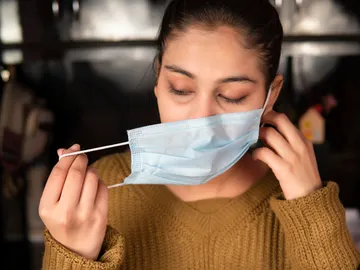 Chica quitándose la mascarilla Chica quitándose la mascarilla