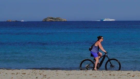 Una mujer pasea con su bicicleta por Ibiza Una mujer pasea con su bicicleta por Ibiza
