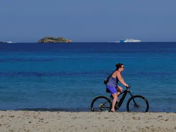 Una mujer pasea con su bicicleta por Ibiza