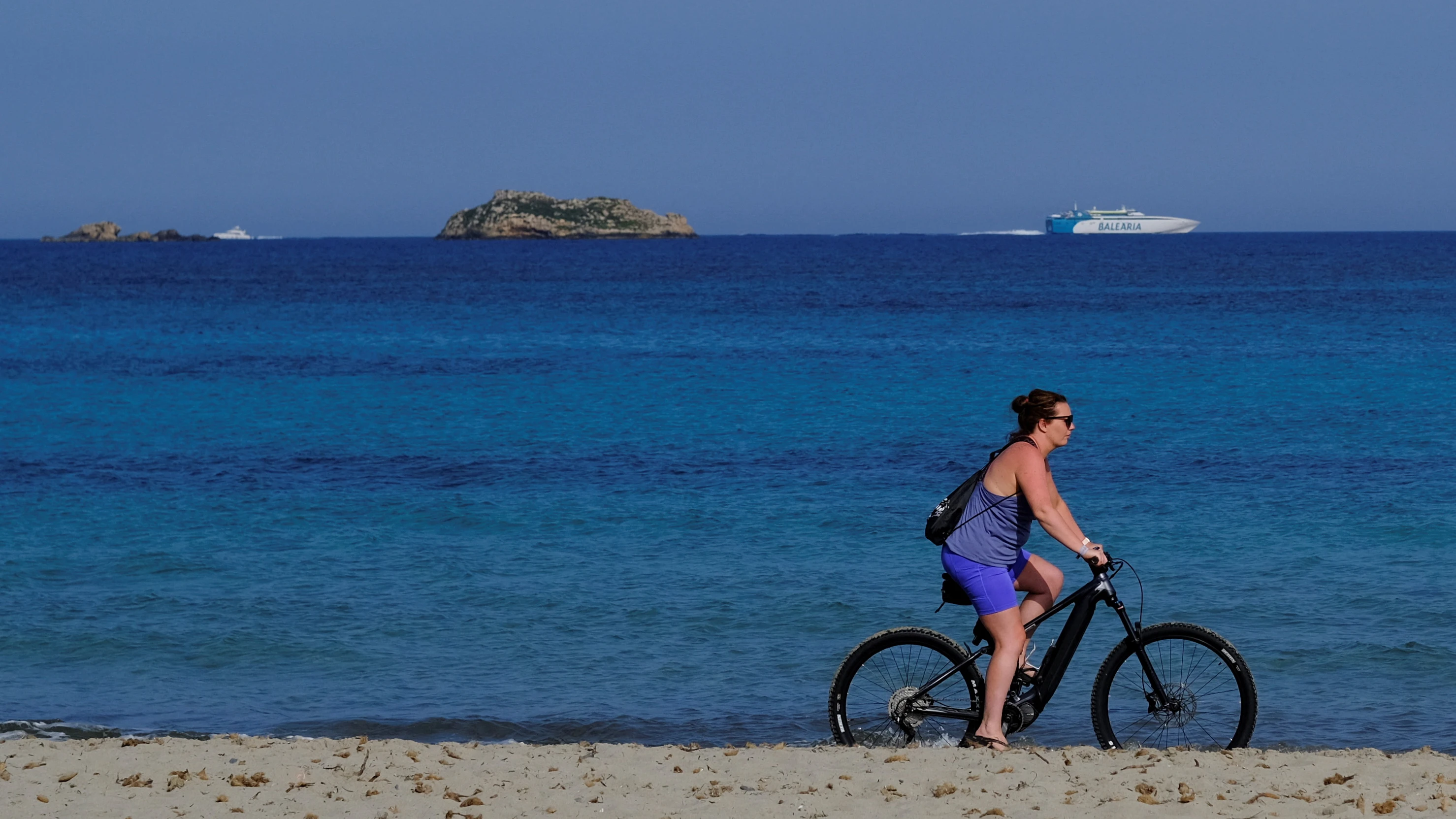 Una mujer pasea con su bicicleta por Ibiza