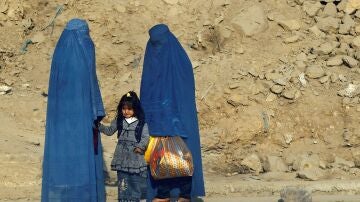  Mujeres afganas vestidas con burkas esperan transporte en una carretera en Kabul