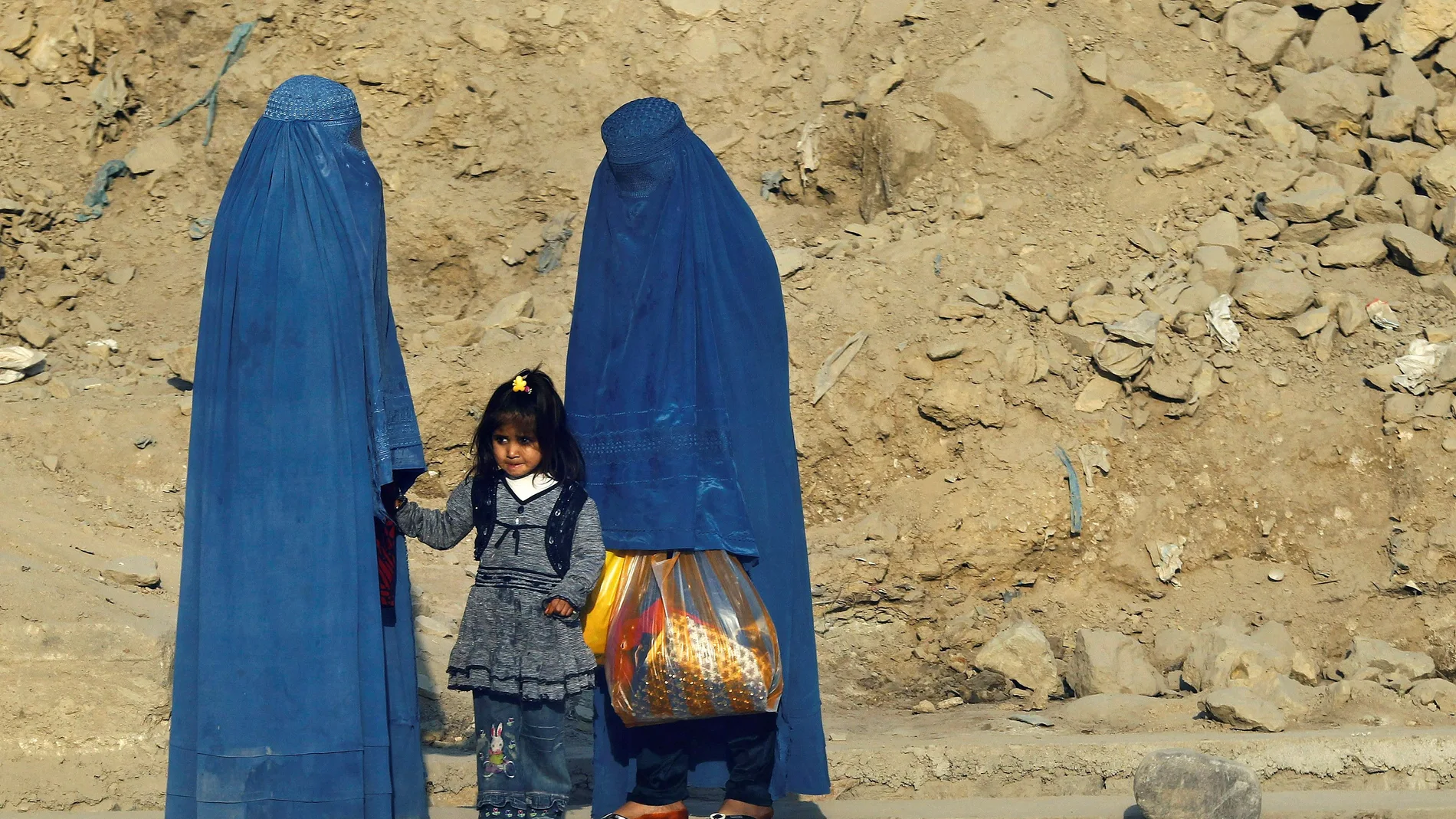 Mujeres afganas vestidas con burkas esperan transporte en una carretera en Kabul