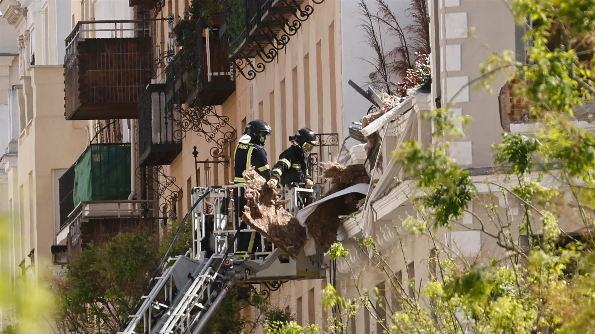 Los bomberos trabajan entre los escombros del edificio que ha sufrido una explosión.