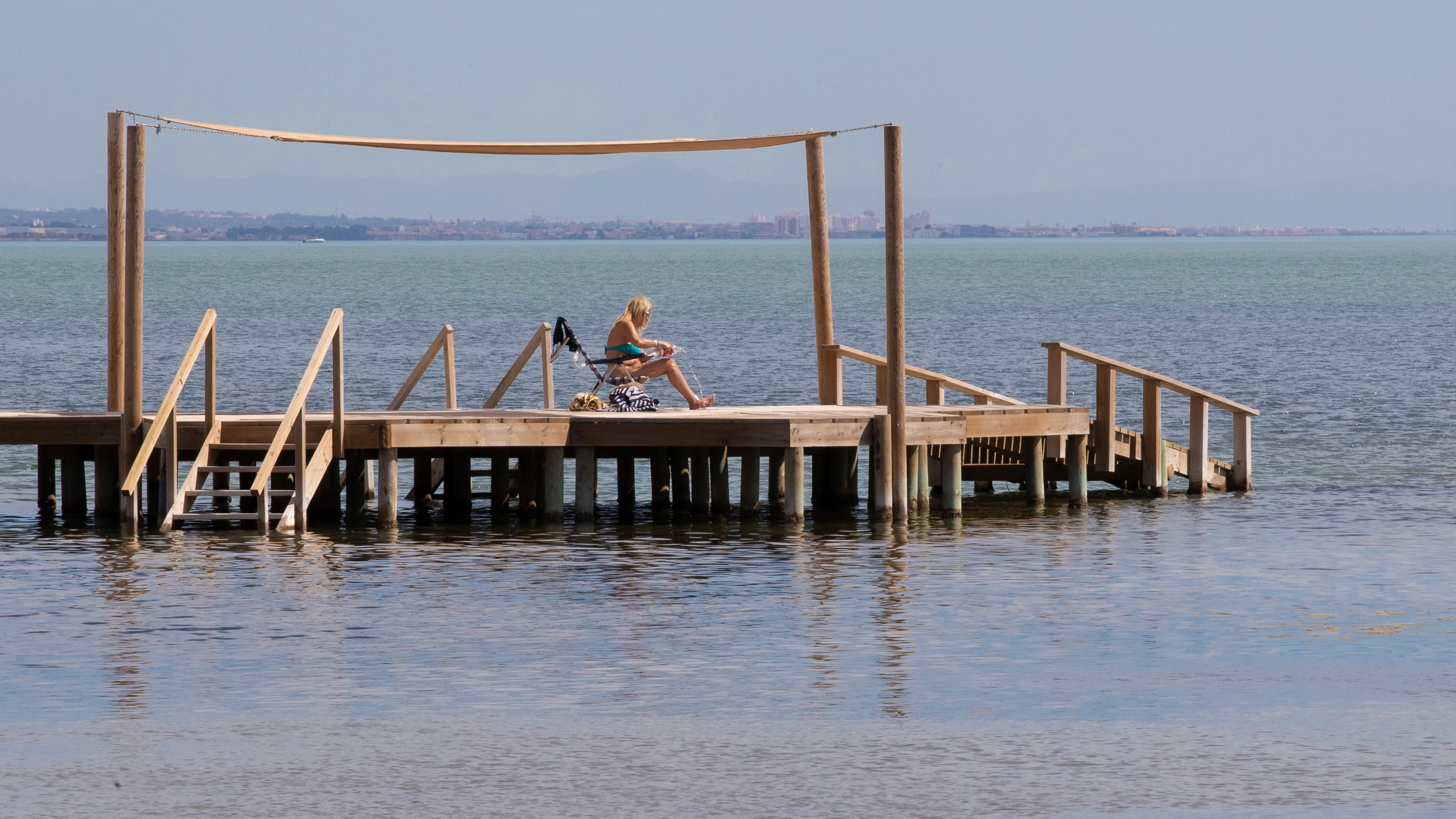 Una mujer se refresca el cuerpo con agua mientras toma el sol este domingo en la playa de los Urrutias, en el Mar Menor.
