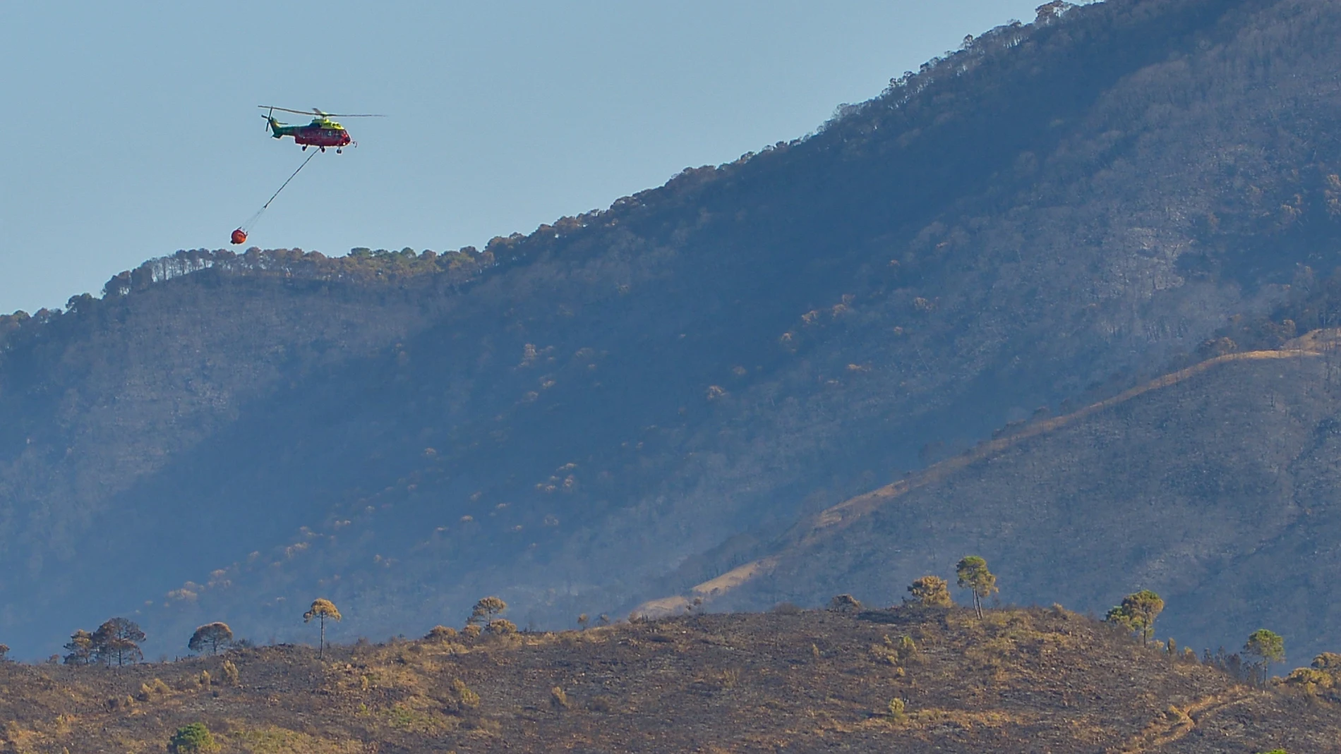 Un helicóptero sobrevuela la zona afectada por el incendio acontecido de Pujerra