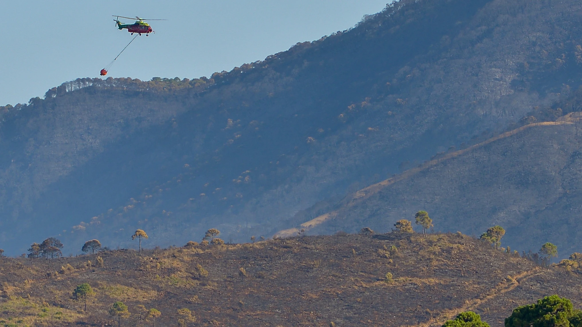 Un helicóptero sobrevuela la zona afectada por el incendio acontecido de Pujerra