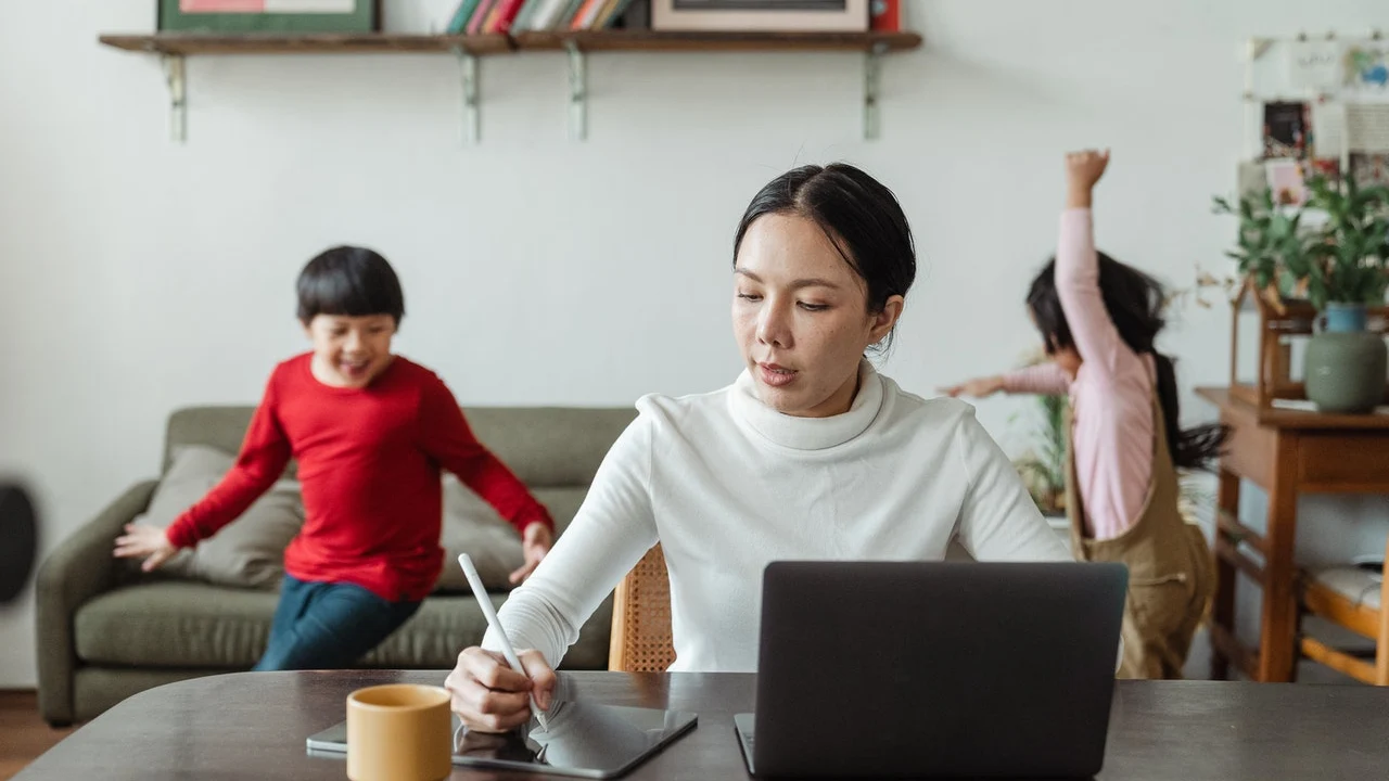 Una madre teletrabaja desde su casa mientras cuidad a la vez de sus dos hijos