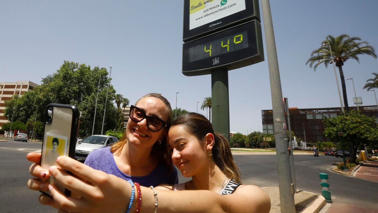 Dos personas se hacen un selfie frente a un term&oacute;metro que marca 44 grados en C&oacute;rdoba 